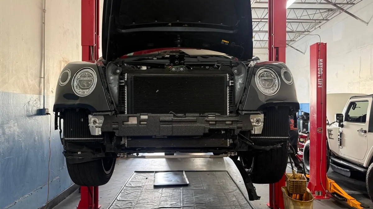 Box de serviço com um Bentley no elevador e um Jeep ao lado