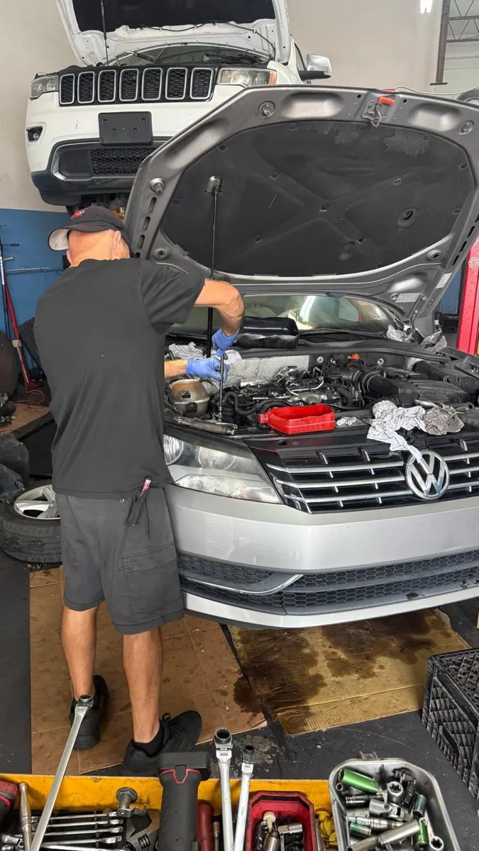 Mecânico trabalhando no motor de um Volkswagen na oficina