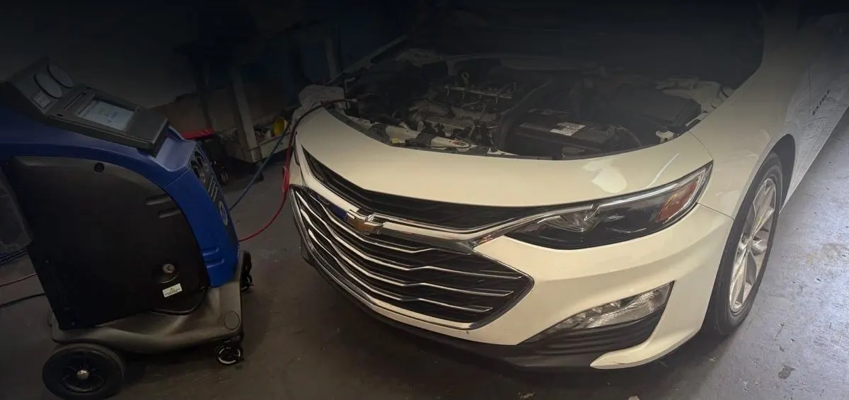 Car air conditioning service with the A/C recharge machine connected at Phil's Electric Auto Expert in Pompano Beach